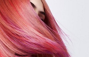 A woman whose face is covered by flowing, red hair